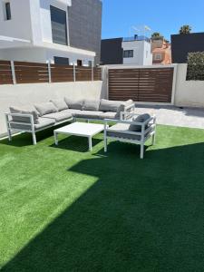 une terrasse avec un canapé et une table sur la pelouse dans l'établissement Brilliant Villa, à Gran Alacant