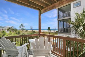 d'une terrasse avec des chaises blanches et une table sur un balcon. dans l'établissement Beach Please by Pristine Properties Vacation Rentals, à Indian Pass