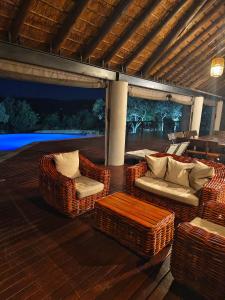 a patio with wicker chairs and tables on a deck at Tholo Private Game Lodge in Bela-Bela