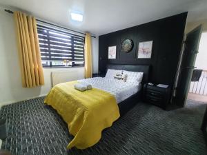a bedroom with a bed with a yellow blanket on it at Professional Stay Doctors Nurses Trades in Luton