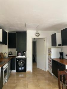 une cuisine avec des armoires noires et un lave-linge/sèche-linge dans l'établissement Terre et mer, à Urrugne