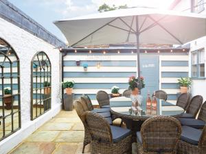 a patio with a table and chairs and an umbrella at The Old Coach House in Henley on Thames
