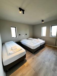 two beds in a room with two windows at The Greyhouse "Big Apartment" in Höfn