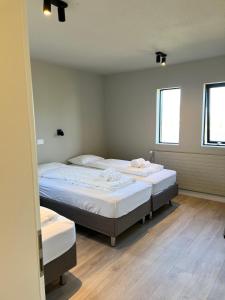 two twin beds in a room with two windows at The Greyhouse "Big Apartment" in Höfn