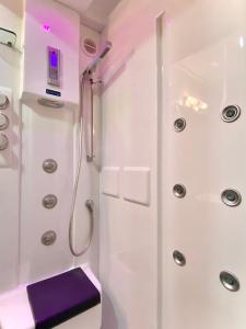 un bagno bianco con una doccia con un sedile viola di Torre Luxor a León