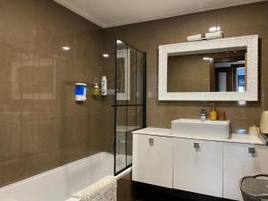 un bagno con un lavandino, uno specchio e una vasca di Torre Luxor a León