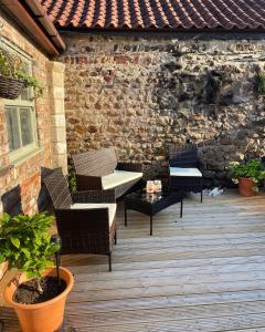 a patio with chairs and tables and a brick wall at Swallow Cottage in Ripon