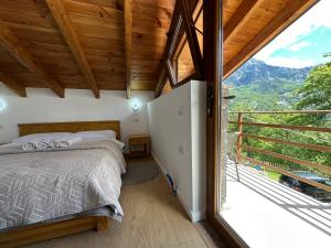 Un dormitorio con una cama y una ventana grande. en Bujtina Carku, en Theth