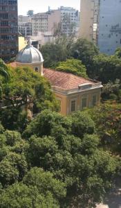 Loft Aconchegante no Centro de Niterói!! في نيتيروي: مبنى اصفر بسقف احمر محاط بالاشجار