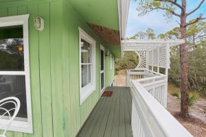 a green house with white windows and a porch at Oceans of Time by Pristine Properties Vacation Rentals in Indian Pass