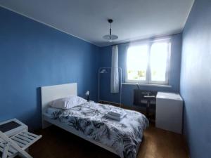 Dormitorio azul con cama y ventana en Seaside Apartment, en Gdansk