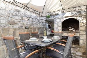 a table and chairs in front of a stone fireplace at House Villa Danica on the hills in Srinjine