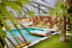 a swimming pool with two beds and palm trees at SANIMAR By Mono Alex in Kassandra
