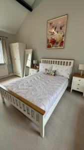 a bedroom with a large bed with white furniture at Swallow Cottage in Ripon