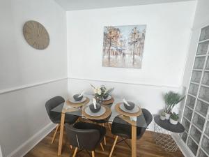 a dining room with a table and chairs and a clock at St Albans City Stays - Near Luton Airport - St Albans Abbey & City Train station - Close to London- Harry Potter World - The Odyssey Cinema - Abbey Cathedral- Contractors I Business I Leisure- sleeps upto 6 people in Saint Albans