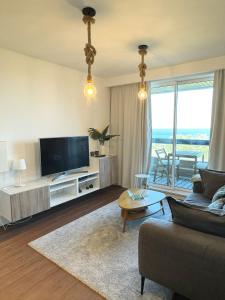uma sala de estar com uma televisão de ecrã plano e um sofá em Alto da Barra *Ocean View em Oeiras