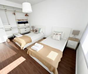 Duas camas num pequeno quarto com paredes brancas em Alto da Barra *Ocean View em Oeiras
