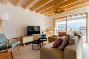 een woonkamer met een bank en een televisie bij Appartement Duplex vue lac et montagne à Talloires in Talloires