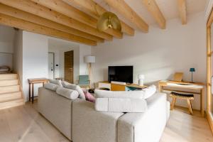sala de estar con sofá blanco y TV en Appartement Duplex vue lac et montagne à Talloires en Talloires