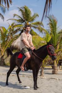 a man sitting on a horse on the beach at Paraíso Natural Ecohotel in San Bernardo del Viento