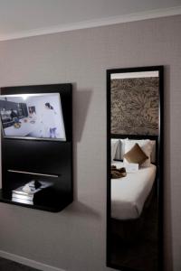 a mirror in a room with a bed and a tv at Best Western Allegro Nation in Paris