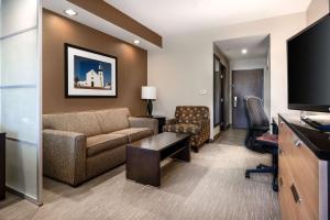 a living room with a couch and a tv at Best Western Premier Bryan College Station in Bryan