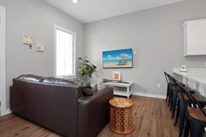 a living room with a leather couch and a table at Sazerac by Pristine Properties Vacation Rentals in Port Saint Joe