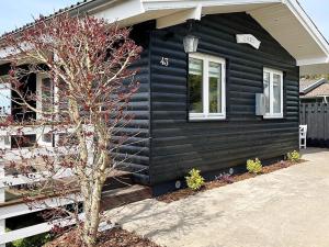 Una casa negra con un árbol delante. en 4 person holiday home in Faaborg en Bøjden