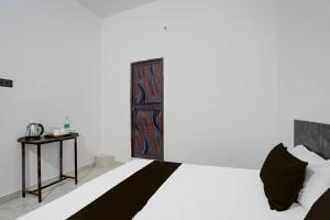 a bedroom with a bed and a table and a door at OYO Flagship Hotel J. S in Kānpur
