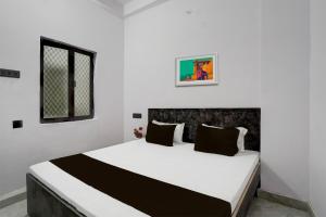 1 dormitorio con 1 cama blanca grande con almohadas negras en OYO Flagship Hotel J. S, en Kānpur