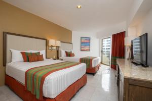 Tesoro Ixtapa Beach Resort في اكستابا: غرفة فندقية بسريرين وتلفزيون بشاشة مسطحة