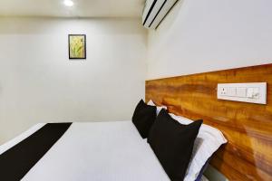 1 dormitorio con cama blanca y cabecero de madera en OYO Hotel New Hitech Inn, en Hyderabad