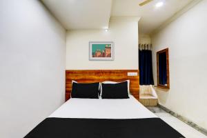 1 dormitorio con cama blanca y almohadas negras en OYO Hotel New Hitech Inn, en Hyderabad