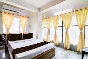 1 dormitorio con 1 cama y ventanas con cortinas amarillas en OYO RELAXING PARADISE, en kolkata