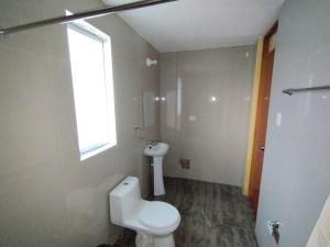 La salle de bains est pourvue de toilettes blanches et d'une fenêtre. dans l'établissement Antawara, à Chivay
