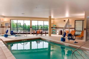 einen Pool in einem Haus mit einem Wohnzimmer und einem Esszimmer in der Unterkunft Courtyard by Marriott Indianapolis Noblesville in Noblesville