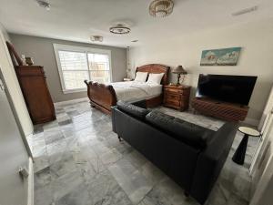a bedroom with a bed and a couch and a television at Stylish Bungalow Near Dining, Parks & Entertainment in Jacksonville