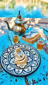 - une assiette de bananes sur une table avec une bouilloire dans l'établissement RIAD AMAN SKOURA, à Skoura