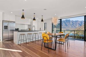 une cuisine avec une table et des chaises ainsi qu'une grande fenêtre dans l'établissement Style & Tranquillity - Eight Bedrooms, Two Houses, à Queenstown