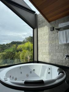 Pinto Bandeira的住宿－CABANAS LE VIGNE，带浴缸的浴室和大窗户