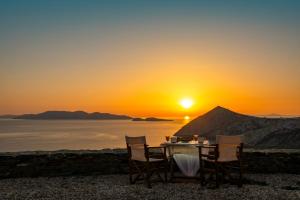 stół i krzesła z zachodem słońca w tle w obiekcie Aegean Balcony Studio w mieście Áno Meriá