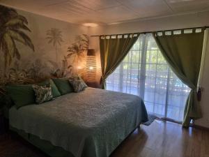 a bedroom with a bed and a large window at Hinakena Colonial Villa in Papara