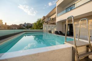 a swimming pool with two chairs next to a house at Luxury villa with a swimming pool Makarska - 23218 in Makarska
