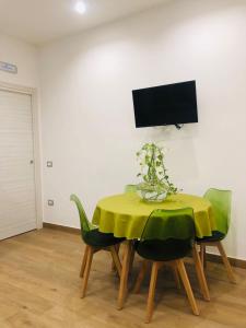 a dining room table with a yellow tablecloth and green chairs at Green House GM in Gragnano