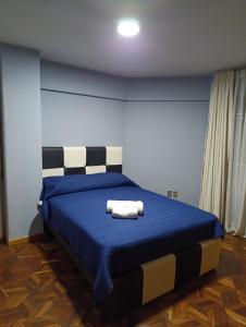 a bedroom with a blue bed with two towels on it at Céntrico y confortable in La Paz