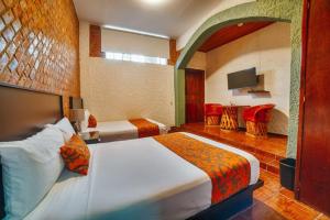 una camera d'albergo con due letti e una televisione di Hotel Casa Tequis San Luis Potosi a San Luis Potosí