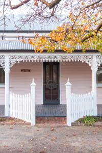 a white house with a porch and a white fence at Isabellas At Beechworth in Beechworth