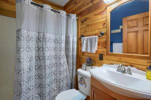 a bathroom with a shower curtain and a sink at Blue Rose Cabins - Lincoln Log Cabin in Logan