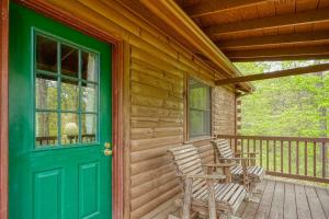 a porch with two rocking chairs and a green door at Blue Rose Cabins - Lincoln Log Cabin in Logan