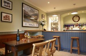 a bar with a wooden table and some wine glasses at Y Meirionnydd Boutique Hotel in Dolgellau